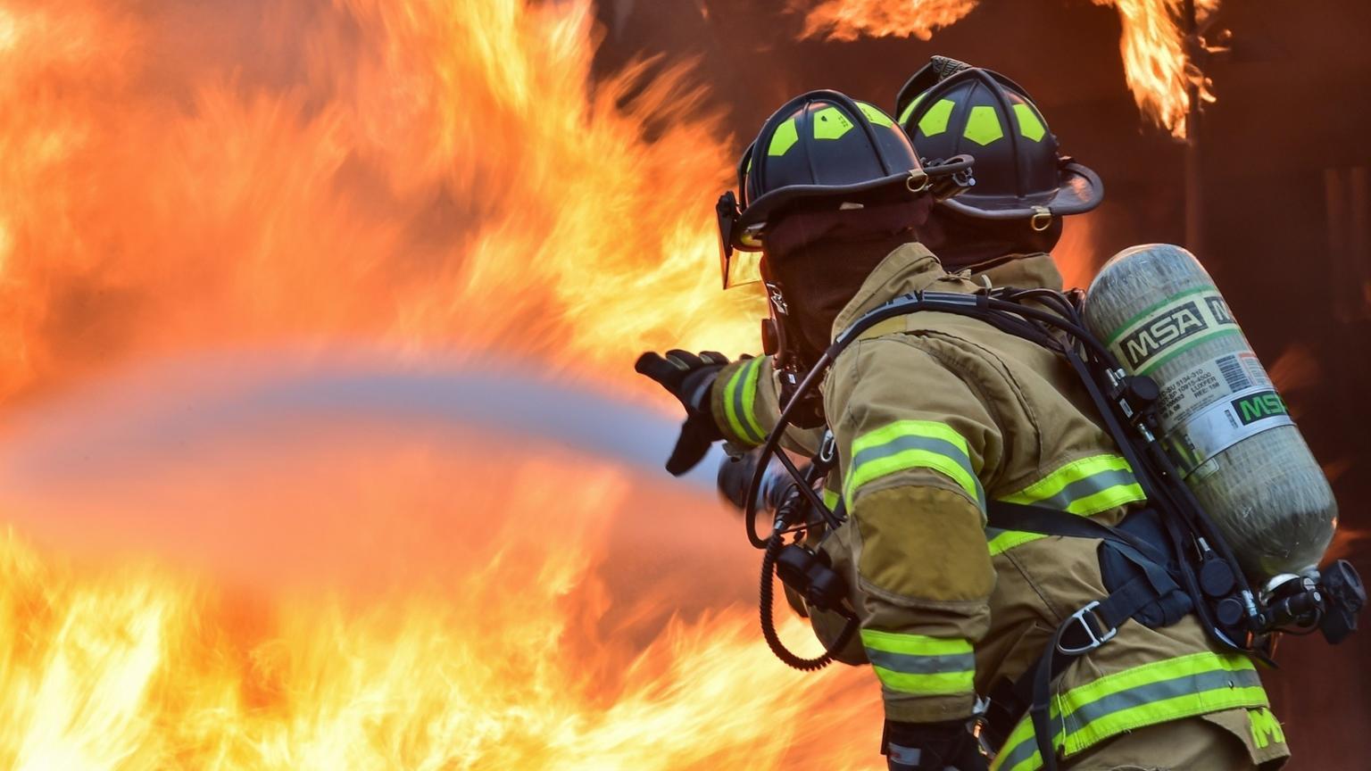 This photo shows a firefighter holding a hose fighting a big blaze