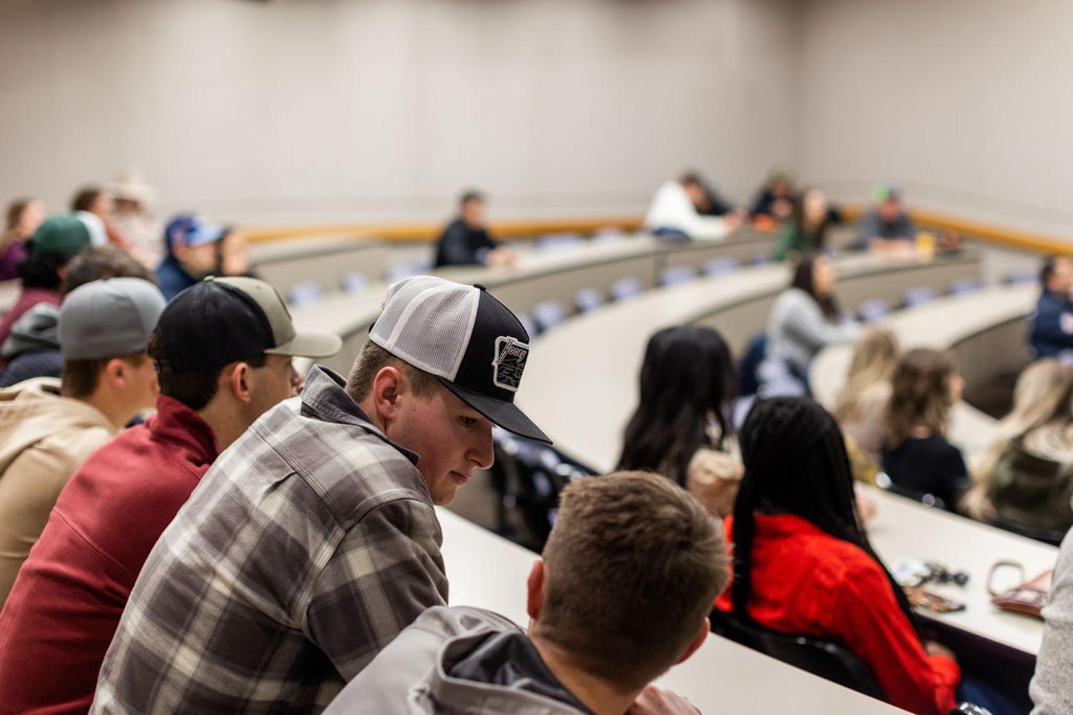 Students sitting in a lecture hall listening to a presenter.