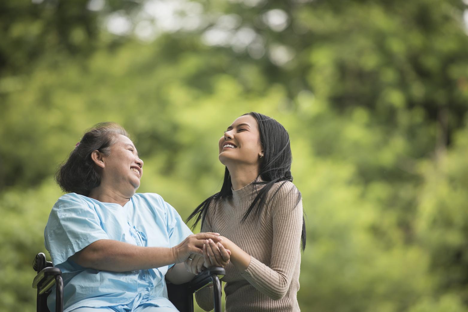 an elderly woman and young women are sitting next to each other smiling while looking up in the sky